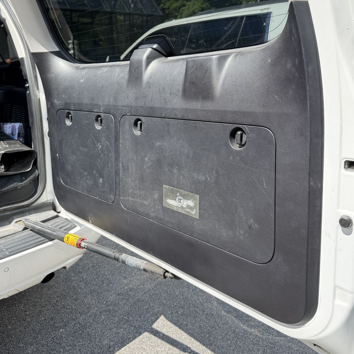 SUV rear hatch interior panel before cleaning, trim streaked with grime and dust