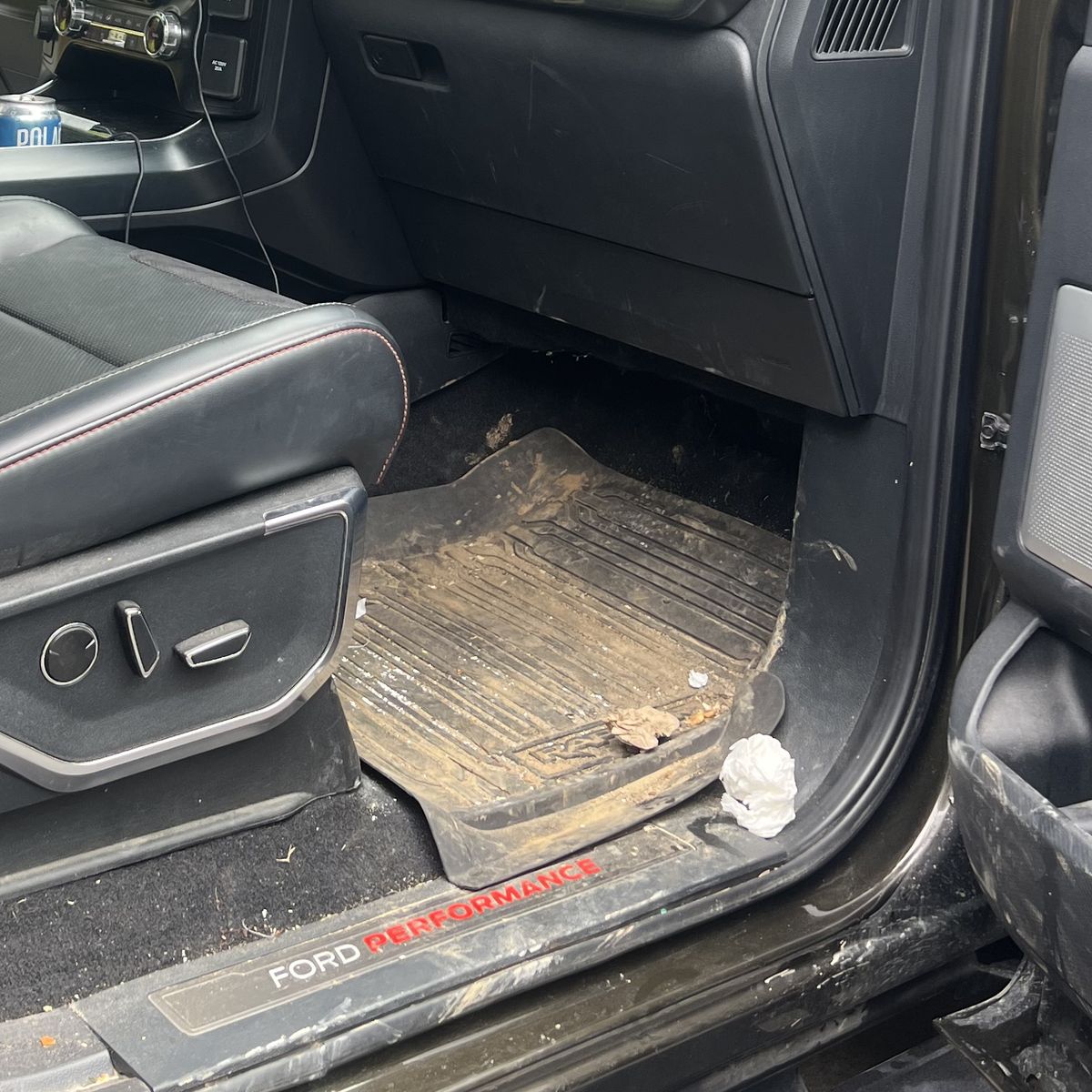 Truck driver footwell before cleaning, floor mat and carpet caked with dried mud